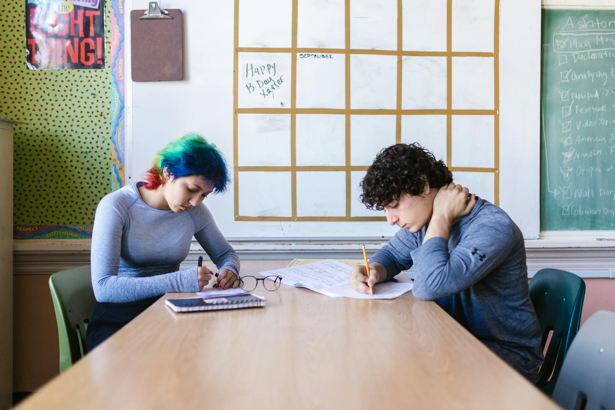 Two students with colorful hair focusing on study sessions in a classroom.